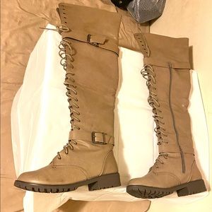 An over-the-knee combat boot featuring a low heel.